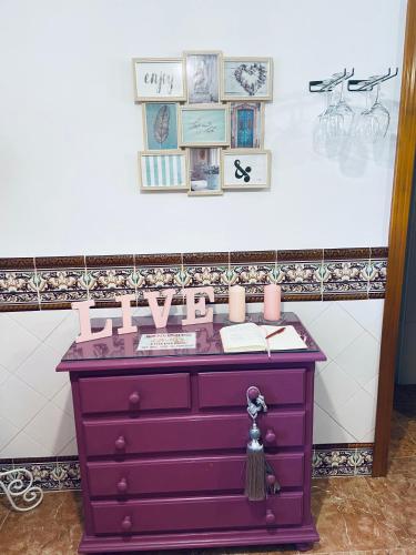 a purple dresser with candles and pictures on a wall at Casa Hay que Vivir el Momento in Setenil
