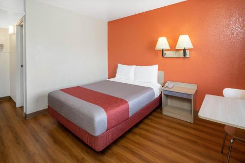 a hotel room with a bed with orange walls at Jurupa Valley, CA - Riverside West 