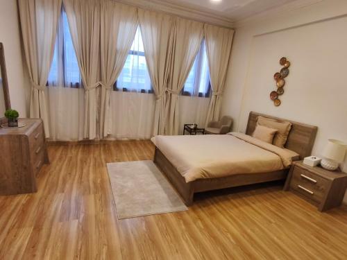 a bedroom with a bed and wooden floors and windows at Sada Compound (Women Only) سيدات فقط in Riyadh