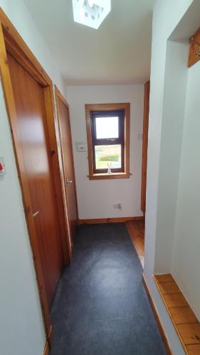 an empty hallway with a window in a house at Rhumhor in Bunessan