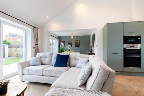 a living room with a white couch and a kitchen at Comfortable & Contemporary 5-Bed 3 Bathroom Home in Gloucestershire