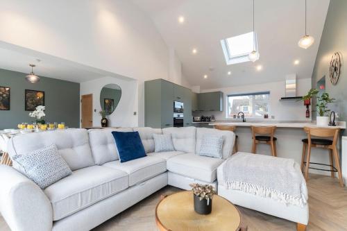 a living room with a white couch and a kitchen at Comfortable & Contemporary 5-Bed 3 Bathroom Home in Gloucestershire
