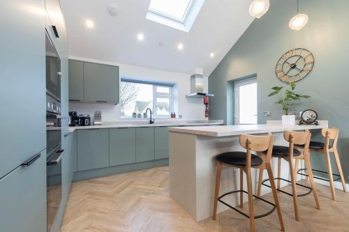 a kitchen with blue cabinets and a counter with stools at Comfortable & Contemporary 5-Bed 3 Bathroom Home in Gloucestershire