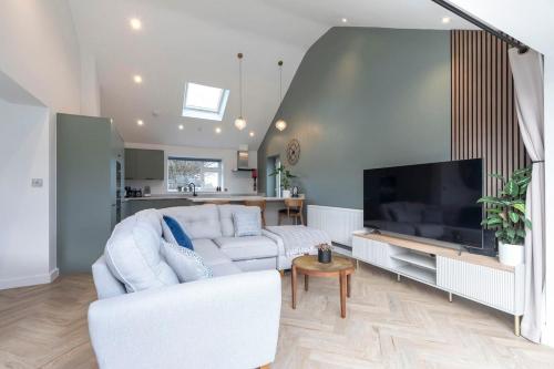 a living room with a white couch and a flat screen tv at Comfortable & Contemporary 5-Bed 3 Bathroom Home in Gloucestershire
