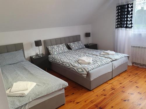 a bedroom with two beds and a wooden floor at Chwila relaksu in Rybarzowice