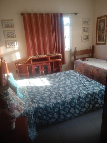 a bedroom with two beds and a chair and a window at Apartamento Piúma in Piúma