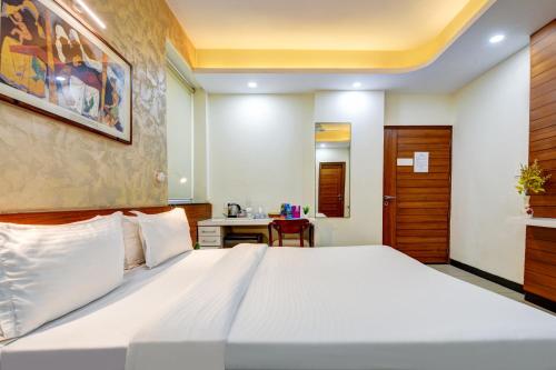a bedroom with a large white bed and a desk at National YMCA Hostel in New Delhi