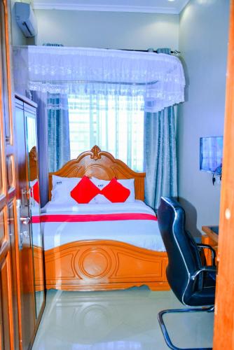 a bedroom with a wooden bed with red pillows at KER HOTEL Dodoma in Dodoma