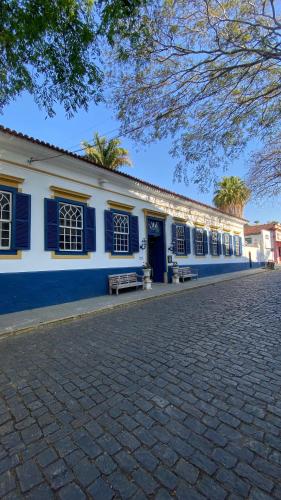 a blue and white building with a bench in front of it at Mara Palace Hotel in Vassouras