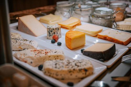 a table topped with different types of cheeses and cakes at Der Kirchheimerhof - Superior in Bad Kleinkirchheim