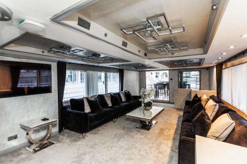 a living room with black leather furniture and windows at The Canary Yacht in London