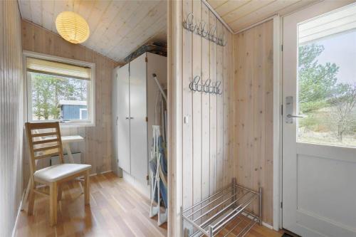 a room with wooden walls and a chair and a door at BL489-Pandrup-Rodhusparken-24 in Pandrup
