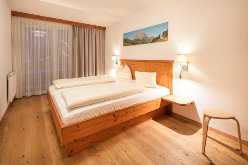 a bedroom with a bed and a chair in it at Apparthotel AlpenChalet in Neukirchen am Großvenediger