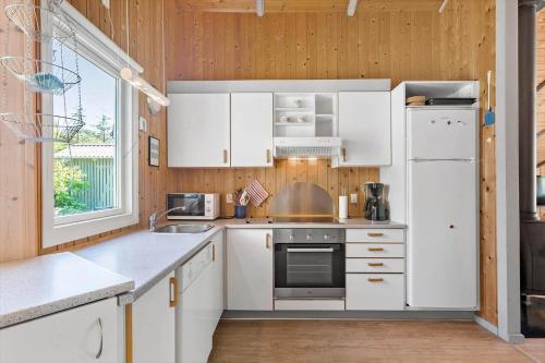 a kitchen with white cabinets and a white refrigerator at BL1374-Saltum-Sydvestpassagen-8 in Saltum