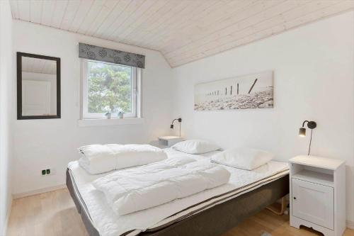 un grande letto bianco in una camera bianca con finestra di BL381-Blokhus-Maxvej-4 a Blokhus