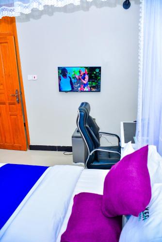 a bedroom with a bed with a purple pillow and a chair at KER HOTEL Dodoma in Dodoma