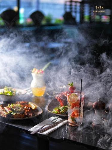 a table with plates of food and drinks and smoke at Grovefield House Hotel in Slough