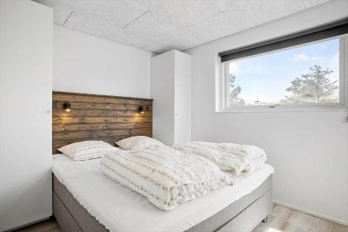 ein weißes Schlafzimmer mit einem großen Bett und einem Fenster in der Unterkunft BL1405 Blokhus - Sletten 12 in Blokhus