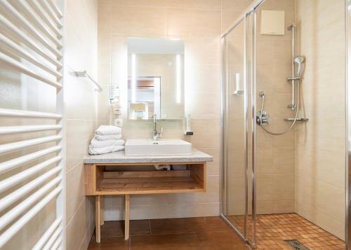 a bathroom with a sink and a shower at Hotel Vitaler Landauerhof in Schladming