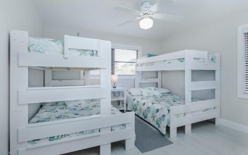 a white bedroom with two bunk beds and a bed at Rock'n Waterfront in Cape Coral