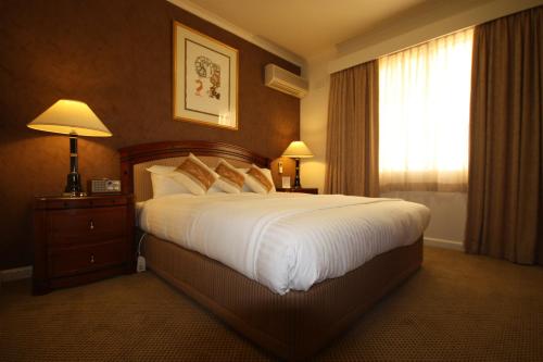 a hotel room with a large bed and a window at Country Plaza Motel in Queanbeyan