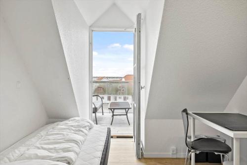 a bedroom with a bed and a desk and a balcony at BL1260-Blokhus-Strandvejen-14-Lejl-9 in Blokhus