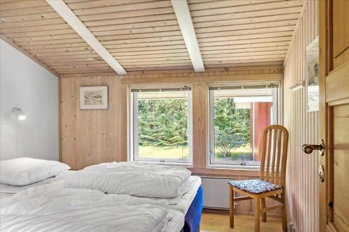 a bedroom with two beds and a chair and two windows at BL410-Saltum-Store-Fiskerbanke-4 in Saltum