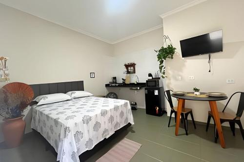 a bedroom with a bed and a table and a tv at Studio kitnet apart. Jundiaí 04 in Jundiaí