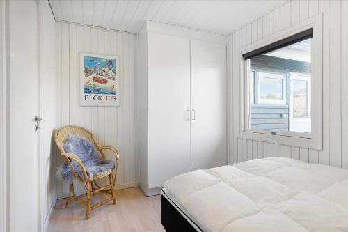 a bedroom with a bed and a chair next to a window at BL1680-Blokhus-Klitgaardsvej-18 in Blokhus