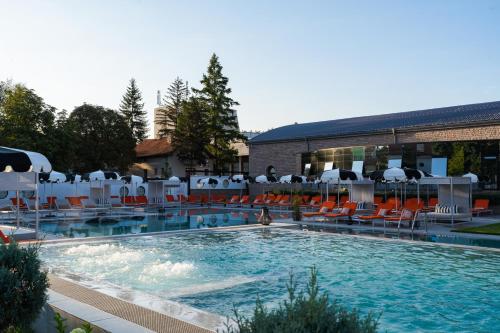 a large swimming pool with chairs and a building at Kamengrad Hotel & SPA in Panagyurishte