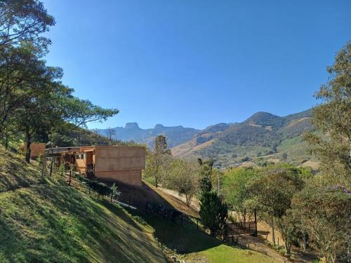 a house on a hill with mountains in the background at Fraga da Mantiqueira in São Bento do Sapucaí