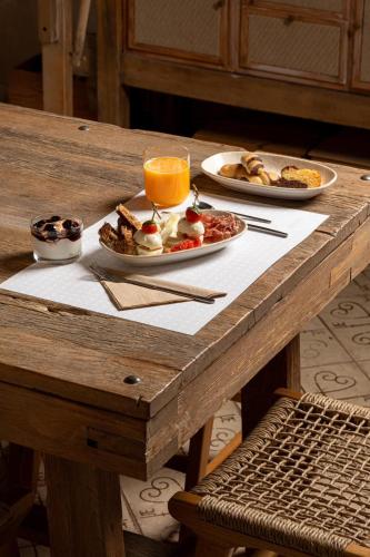 a wooden table with two plates of food and orange juice at Eramai in Patra