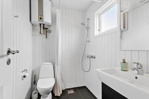 a white bathroom with a toilet and a sink at BL1612-Blokhus-Jens-Baerentsvej-3 in Blokhus