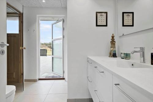 a white bathroom with a sink and a toilet at BL1355-Blokhus-Ribergaardsvej-24 in Blokhus