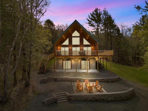 a house with a fire pit in front of it at Luxury Log Cabin Lakefront, Game room & Fire Pit, in Schenevus