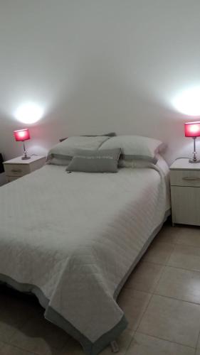 a bedroom with a large white bed with two lamps at Duplex Rawson in Gualeguaychú