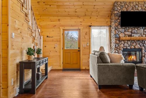 a living room with a couch and a fireplace at Luxury Log Cabin Lakefront, Game room & Fire Pit, in Schenevus