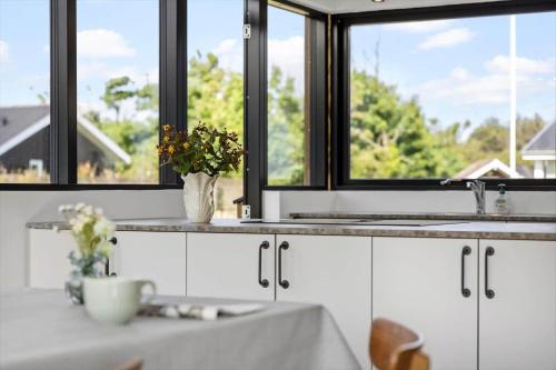 a kitchen with white cabinets and a sink and windows at BL1275-Blokhus-Pirupshvarrevej-17 in Blokhus