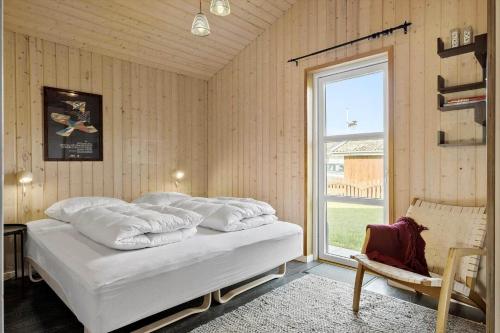 a bedroom with a bed with white pillows and a window at BL1275-Blokhus-Pirupshvarrevej-17 in Blokhus