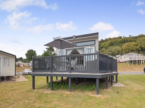 une petite maison sur une terrasse avec un parasol dans l'établissement Highgrove Ledge, à Pendine