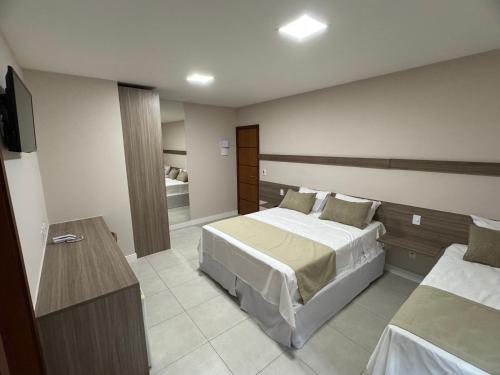 a hotel room with two beds and a television at Hotel Elevare Niteroi in Niterói