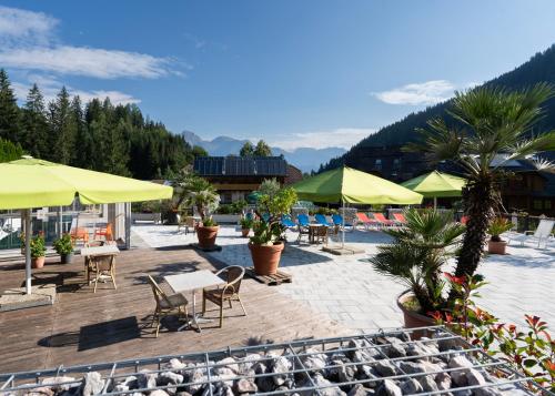 a patio with chairs and tables and yellow umbrellas at Hotel Vitaler Landauerhof in Schladming