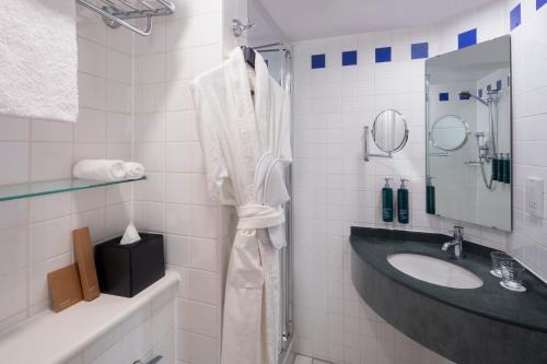 a white bathroom with a sink and a shower at Hilton Garden Inn Bristol City Centre in Bristol