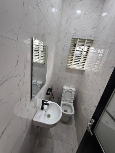 a white bathroom with a sink and a toilet at Muzah Homes Phc in Port Harcourt