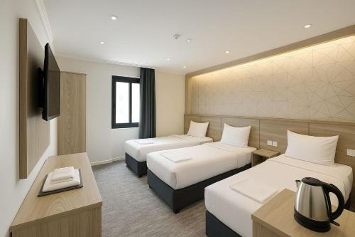 a hotel room with two beds and a television at Nukhbat Al Jiwar Hotel Makkah by Moro in Makkah