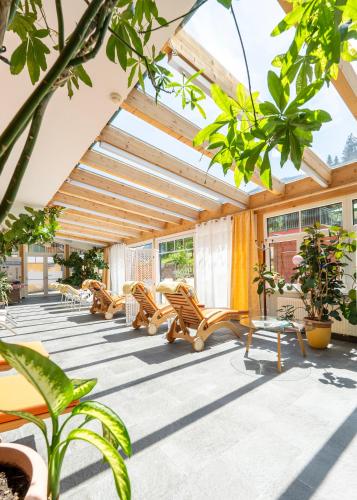 a patio with lounge chairs and plants in a building at Hotel Vitaler Landauerhof in Schladming