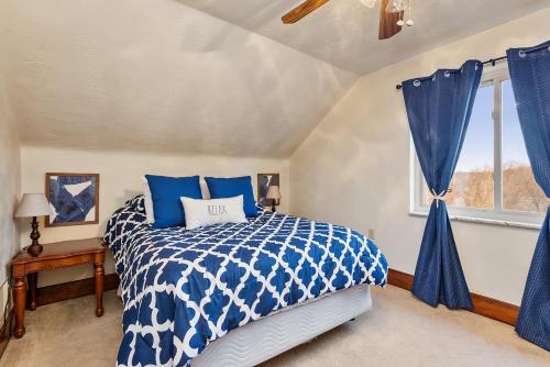 a bedroom with a blue and white bed and a window at Cheerful 4BR Chalet with Seasonal Pool, Hot Tub in New Kensington