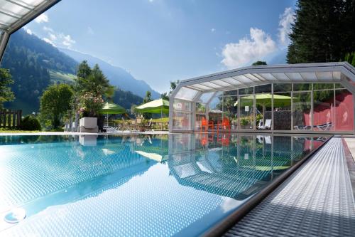 a pool at a resort with mountains in the background at Hotel Vitaler Landauerhof in Schladming