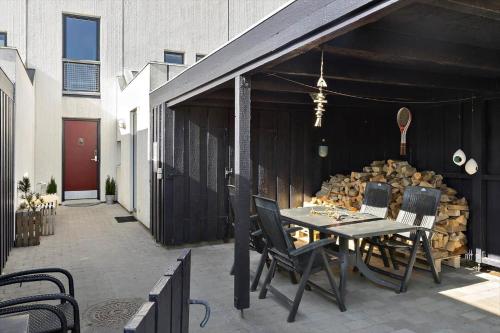 a patio with a table and chairs and a pile of logs at BL1538-Blokhus-Ferren-42 in Blokhus