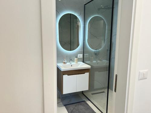 une salle de bain avec un lavabo et deux miroirs dans l'établissement Aleas Apartments, à Durrës